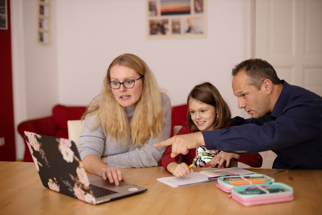 Un parent qui aide son enfant à faire ses devoirs en ligne grâce à l’ordinateur