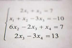 Un élève concentré sur ses exercices de maths, installé à une table de la bibliothèque du lycée.