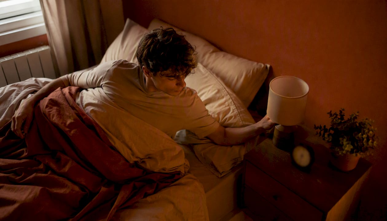Un étudiant éteint sa lampe de chevet avant de s'endormir.