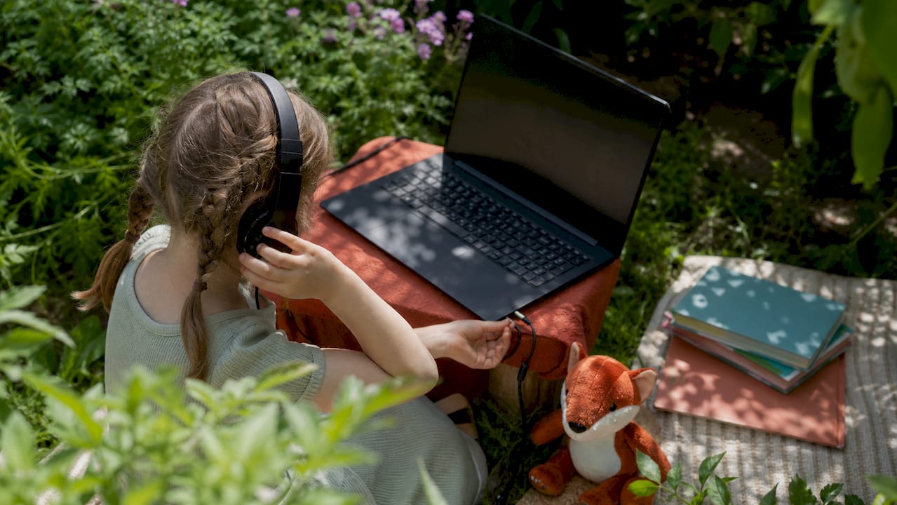 Child setting up laptop and headset for tutoring
