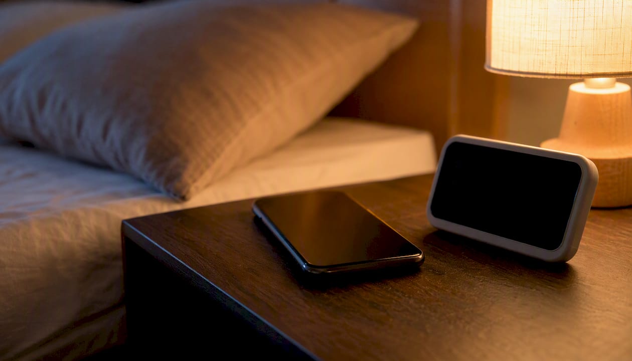 Un smartphone posé sur la table de nuit, avec le mode nuit activé.