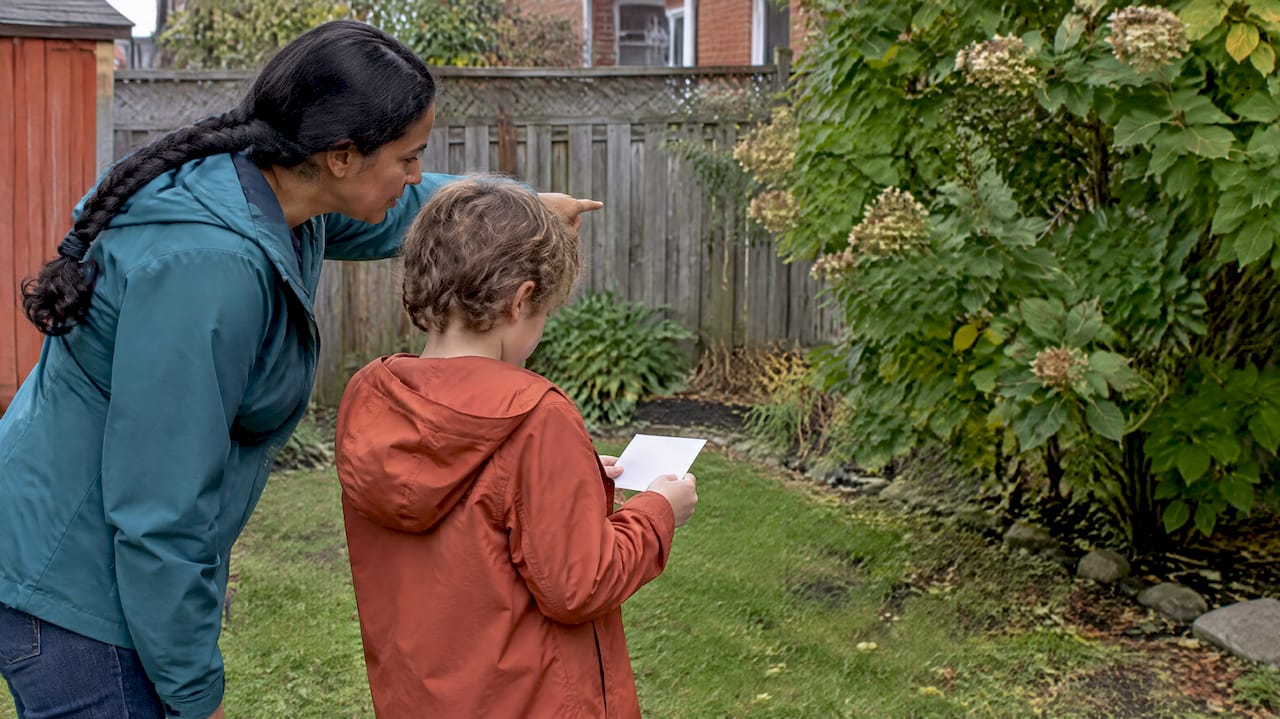 Parent and child follow a backyard clue